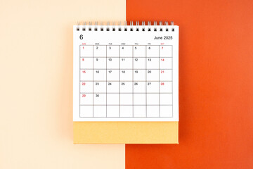 Directly above view of June 2025 desk calendar on orange background.