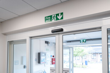 Modern, automatic double sliding doors seen at the exit to a typical NHS hospital outpatients...
