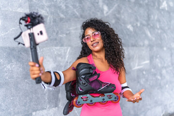 Woman carrying inline skates blogging using mobile outdoors