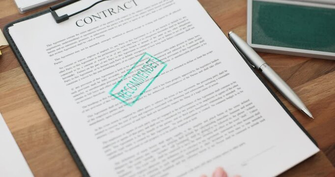 Woman secretary stamps contract with green ink at wooden desk. Company employee marks agreement as legally approved in office setting