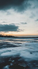 Obraz premium Frozen lake with a dramatic sky at sunset.