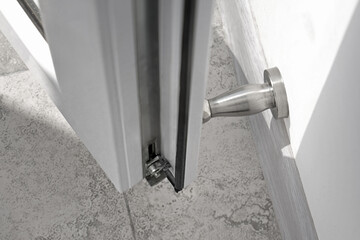 Top view on a stainless steel wall mounted doorstop and metal-plastic door in a renovated apartment...