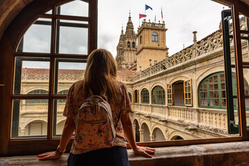 Tourist woman leans out of a cloister window of the University of Santiago de Compostela, Galicia.