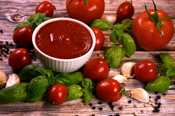 ingredients for making ketchup. ketchup in a white bowl on the table with tomatoes and basil.