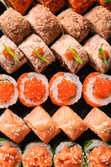 Delicious assortment of colorful sushi rolls artfully arranged on a black platter with vibrant toppings and textures for a culinary feast