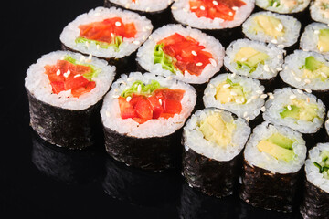 Colorful sushi rolls arranged neatly on a dark surface, showcasing fresh ingredients and intricate craftsmanship in a Japanese culinary display