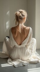 A woman sitting gracefully with her back facing the sunlight in a serene indoor space