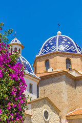 Purple flowers in front of the blue tiled domes of the cathedral in Altea, Spain