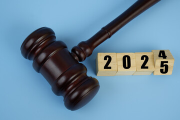 Judge gavel and flipping numbers 2024 and 2025 on wooden cubes. Concept of new laws in year 2025.