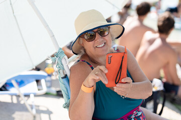 Grandmother enjoying a sunny day at the pool with smartphone
