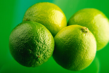 Four lemons lime on a green background, close-up.