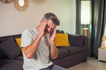 Closeup of man suffering from headache at home, touching his temples, copy space, blurred...