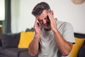 Closeup of man suffering from headache at home, touching his temples, copy space, blurred...