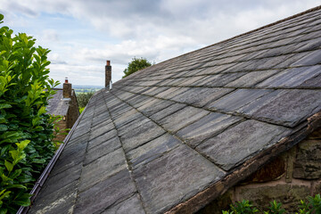 Obraz premium Close-up of a slate roof with lush greenery in the background.