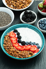 Healthy breakfast . Yogurt with berries ( strawberry , raspberry , blueberry , blackberry ) , granola and chia seeds . Top view