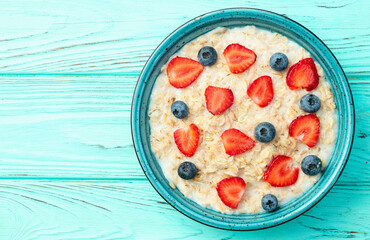 Homemade breakfast . Oatmeal with milk and berries . Top view