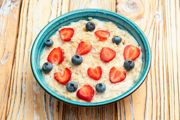 Homemade breakfast . Oatmeal with milk and berries . Top view