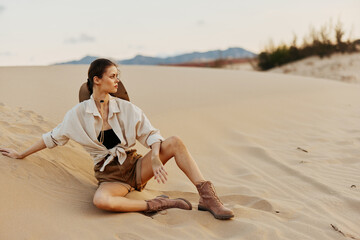 Woman sitting on sand dune in desert under clear blue sky on peaceful summer day