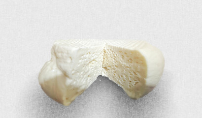 Round white cheese head is cut lying on light background