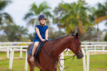 Kids ride horse. Child on pony. Horseback riding.