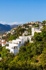 Naklejka premium Villas and buildings perched on cliffs in the city of Roses on the Costa Brava, Spain, from the Castell de la Trinitat
