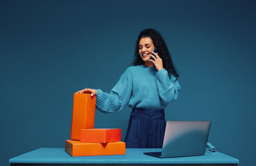 Business woman talking on smartphone next to colorful packages