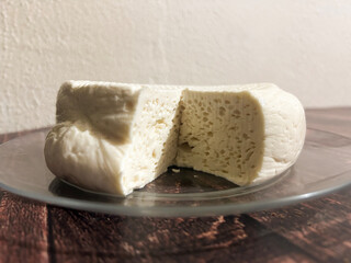 Fresh homemade cheese wheel being sliced on glass plate