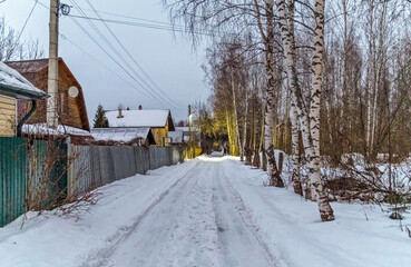 Winter road between houses and trees