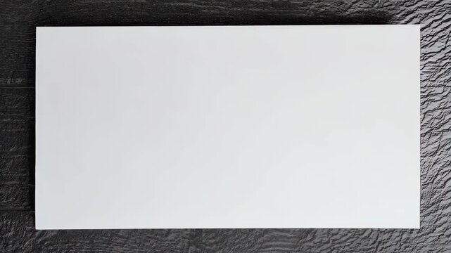 A blank white sheet rests on a textured black surface, creating a striking contrast. minimalist backdrop is perfect for presentations, design projects, and marketing needs.