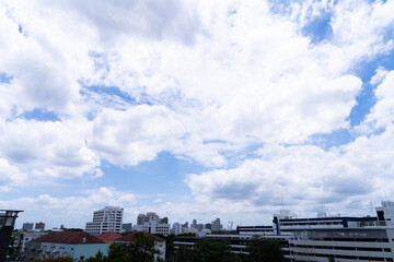 Fototapeta premium Blue sky with white clouds floating above city skyscrapers on a clear summer day