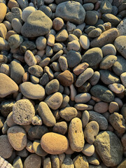 A close-up of round pebbles on the beach at sunset, view from above