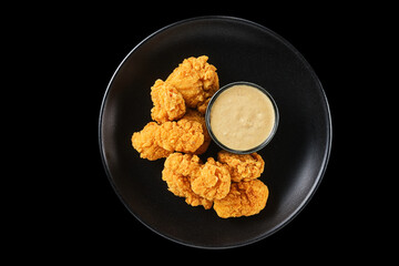 Crispy golden fried chicken served on a sleek black plate with a side of creamy dipping sauce, perfect for a late-night snack