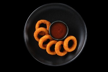Deliciously crispy onion rings served with tangy dipping sauce on a sleek black plate