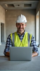 A cheerful construction manager on-site, wearing a hard hat and safety vest, uses a laptop to oversee project management in a modern construction environment.