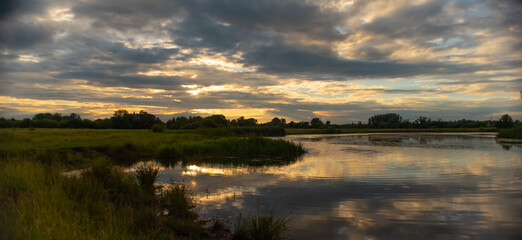 Evening beautiful landscape with cloudy sky and river. The sky is reflected in the water.