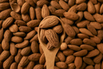 Wooden spoon with raw almonds on a background of almonds, highlighting a healthy natural snack