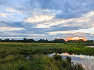 Naklejka premium Evening landscape with a river and clouds. River landscape with the western sun.