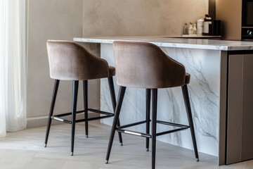 A pair of sleek, modern bar stools with velvet upholstery, positioned before a marble-topped kitchen island and a smooth, high-gloss wall.