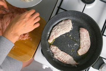 Woman cooking frying breading chicken breast meat in flour on skillet on kitchen at home. Ingredient recipe cuisine culinary. Homemade meal preparation. Protein meat healthy dish.