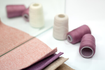 Pink, purple and beige fabric samples, sewing threads in purple colors.