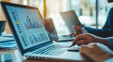 In a vibrant office space, a focused professional analyzes data trends on a laptop while colleagues engage in collaborative discussions during a productive work session