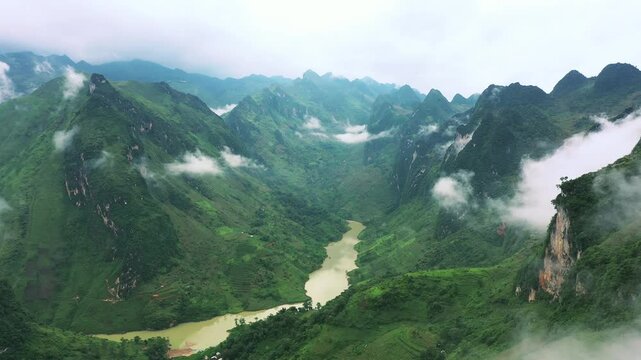 Drone of mountains, clouds and river in nature for travel background, eco tourism location and adventure. Aerial view of green landscape, forest or Asian jungle with fog in Vietnam, Ma Pi Leng Pass