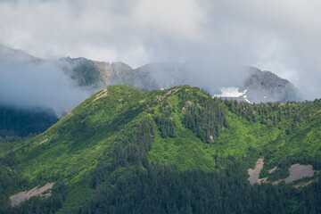 Tall green mountain top covered in clouds in Alaska, USA