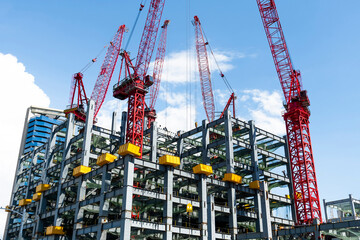 Low-angle view of cranes and steel structures of building construction with a blue sky background in Taiwan.