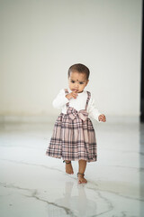 Baby in Plaid Dress, Cute Toddler Fashion, Adorable Baby Portrait, Smiling Baby in Outfit, Toddler in Trendy Dress, Sweet Baby Girl Pose, Stylish Baby Outfit Stock Photo.

