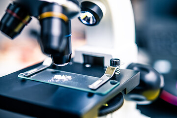 Close-Up of a Microscope with a Glass Slide Holding a Powder Sample for Scientific Research and Laboratory Analysis in a Modern Workspace