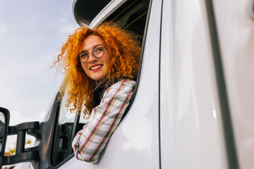 Portrait of professional woman truck driver looking out the window. People and industrial...