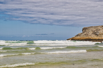 Serene Beach with Gentle Waves and Rocky Cliff at Mawgan Porth Beach, Newquay, Cornwall