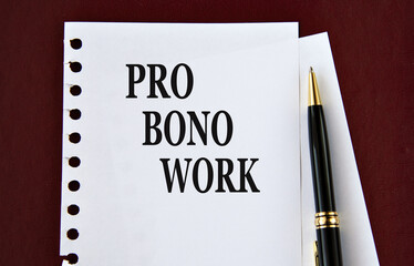 PRO BONO WORK - words on a white sheet on a brown background with a pen