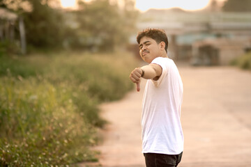 a man standing with a thumbs down. The man acted like someone was underestimating something. set in nature on a sunny afternoon.